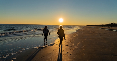 Beach walkers casting long shadows