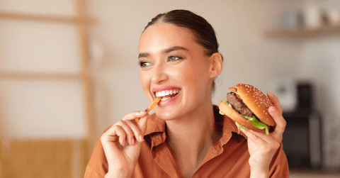 Happy lady eating burger and french fries
