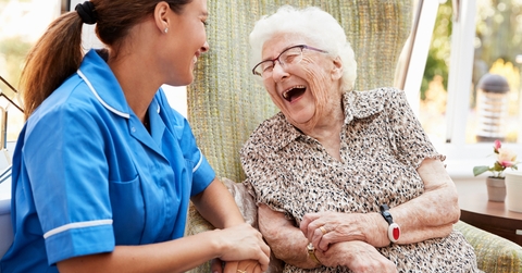 happy senior woman and nurse sitting in chair