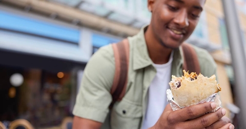 Man Eating Burrito At Outdoor Street Food Stall