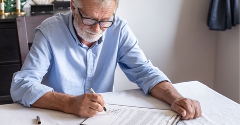 Senior old man elderly examining and signing last will and testament