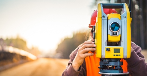 Person using large yellow surveyor camera zoomed with blurry background