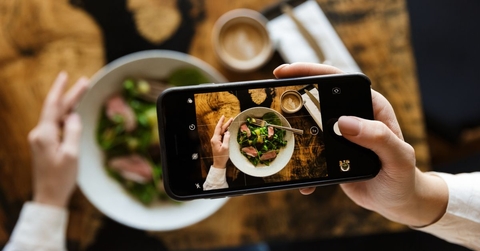 food critic using smartphone to take a photo of their meal