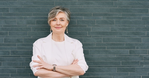 60-year-old woman in a cream blazer again a teal tile background