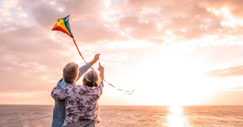 Senior couple flying kite by the water