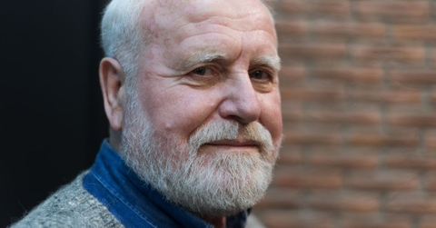 close up of a 70 year old man with a brick wall in the background