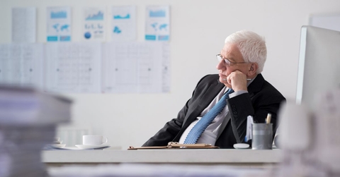older man in suit at office contemplating
