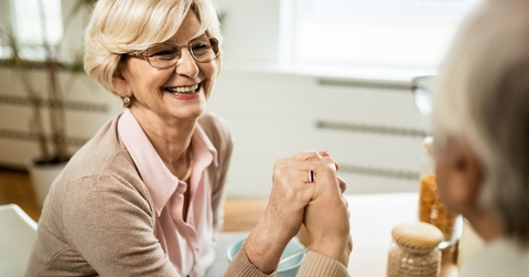 Senior woman holding her spouse&#x27;s hand and smiling