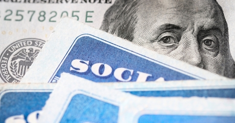Dollar bill with Benjamin Franklin&#x27;s eyes looking and Social Security cards
