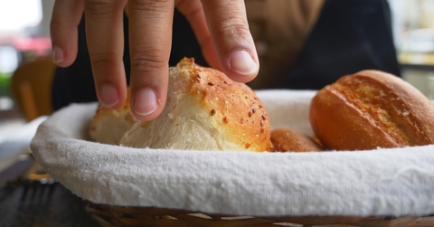 Hand grabbing bread from bread basket at restaurant
