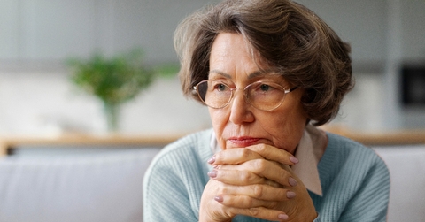 Older woman with hands crossed under her face looking worried