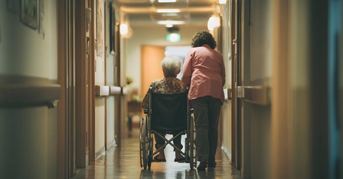 Female Caregiver and Elderly Woman in Hospital Hallway