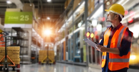 trader worker in orange vest and hardhat in a warehouse