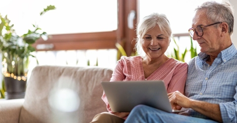 senior couple on couch with laptop