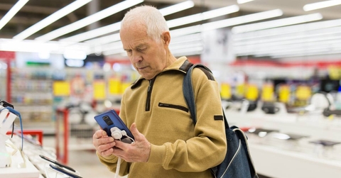 Senor man buying phone in showroom of digital electronic goods store 
