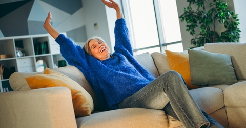 Woman happy and relaxed with arms up on the couch