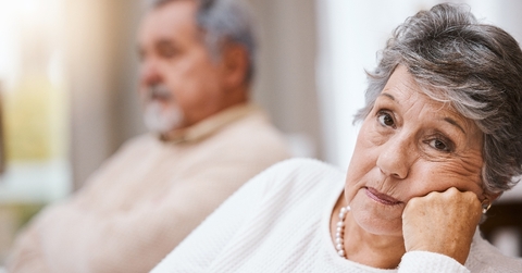 Bored senior woman looking while husband is in the back