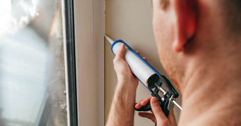 A man caulking a window