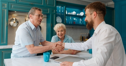 Retired couple in the kitchen shaking hands with young man