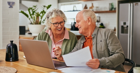 Older couple smiling while working on financial paperwork