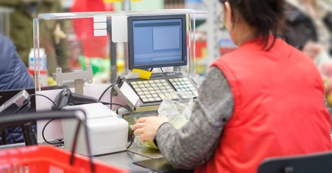 Cash desk with cashier serves customer in modern supermarket 