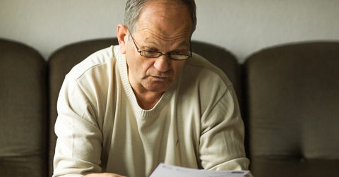 An old man looking at a bill