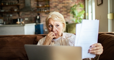 Older woman looking at papers worried face