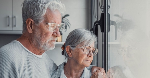 Pensive senior couple looking out window