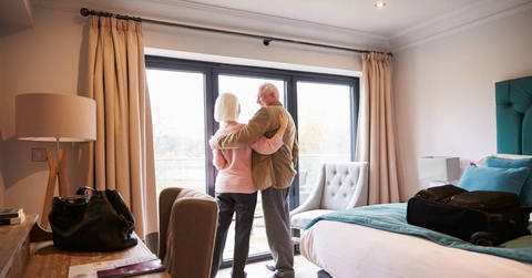 Senior Couple Arriving In Hotel Room On Vacation 