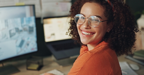 Woman wearing glasses smiling at the camera while working from home