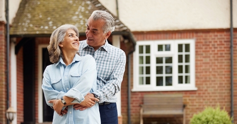 Retired couple hugging in front of the house