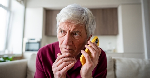 Older man on the phone looking suspicious