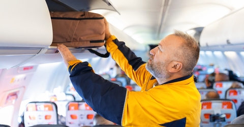 Man putting backpack in overhead bin on airplane 