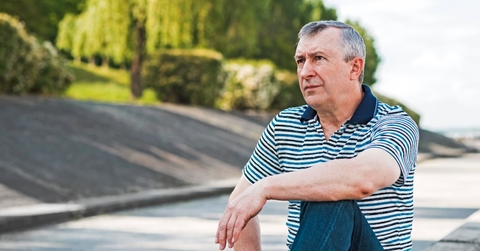 Man in his 50s sitting outdoors looking beyond, thinking
