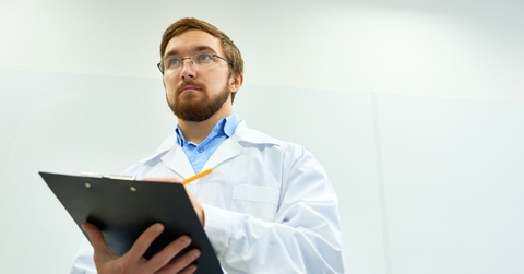 Man wearing lab coat taking notes 