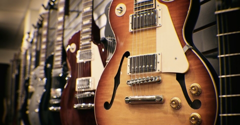 row of guitars on display for sale hanging in a music store