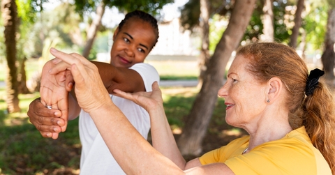 Older woman helping younger woman stretch