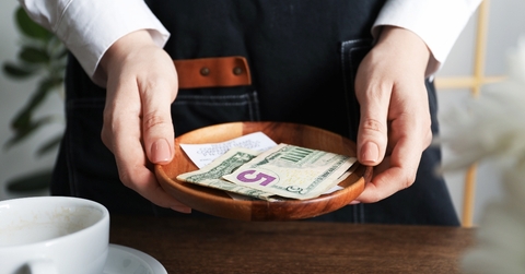 Server holding wood bowl with check and cash tips