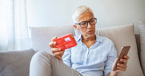 Senior woman looking at medication and phone suprised