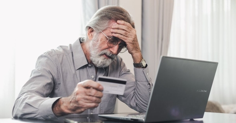 Stressed mature man holding credit card