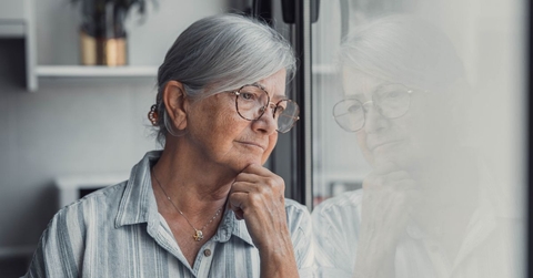 Concerned elderly woman looking out window