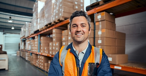 Man in his 40s smiling at camera working in a warehouse