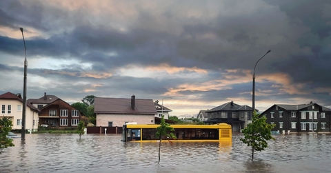 Flooded street with stranded bus and homes around