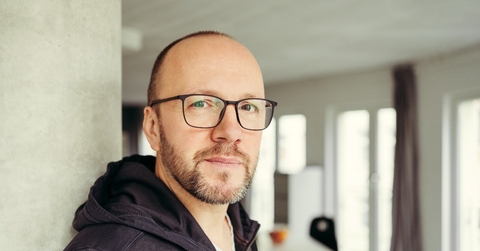 Bald man wearing glasses looking at camera