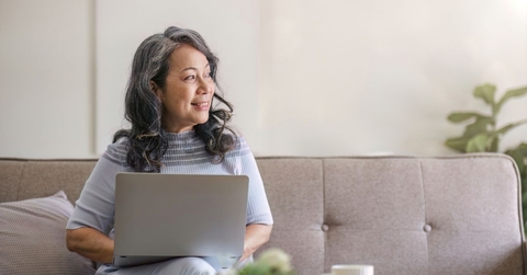 Smiling woman in 60s on couch with laptop