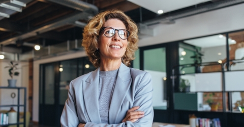 Woman in suit wearing glasses smiling at work