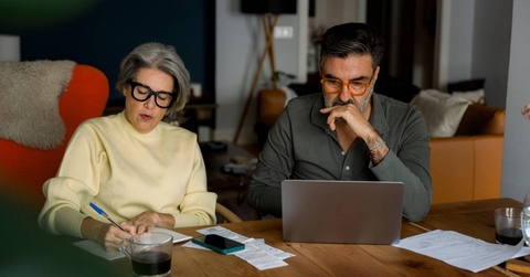 Mature couple managing finances and planning household budget at kitchen table
