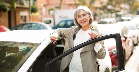 Mature woman standing besides white car