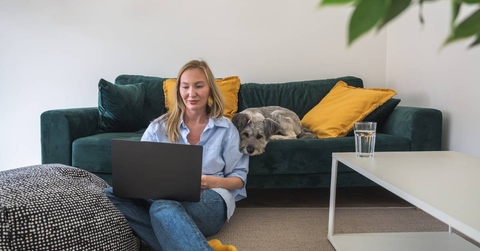woman freelancer working on laptop with her dog at home