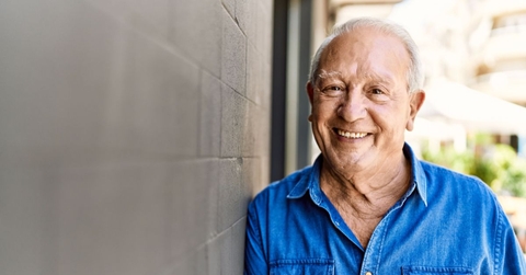 Smiling senior man leaning on concrete wall